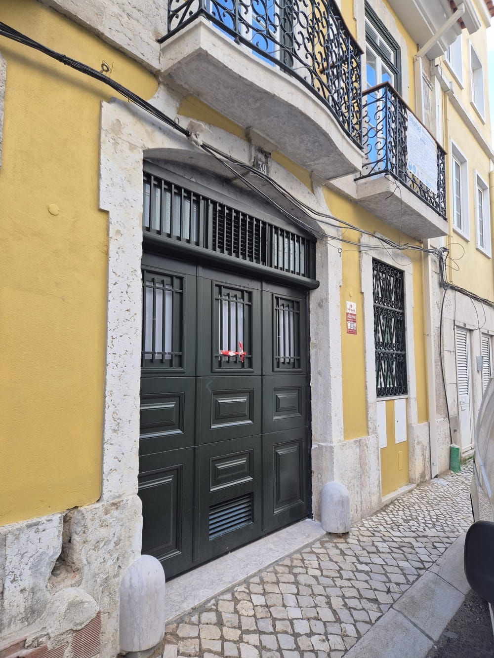 Porta seccionada em madeira de kambala numa fachada em reabilitação em Lisboa