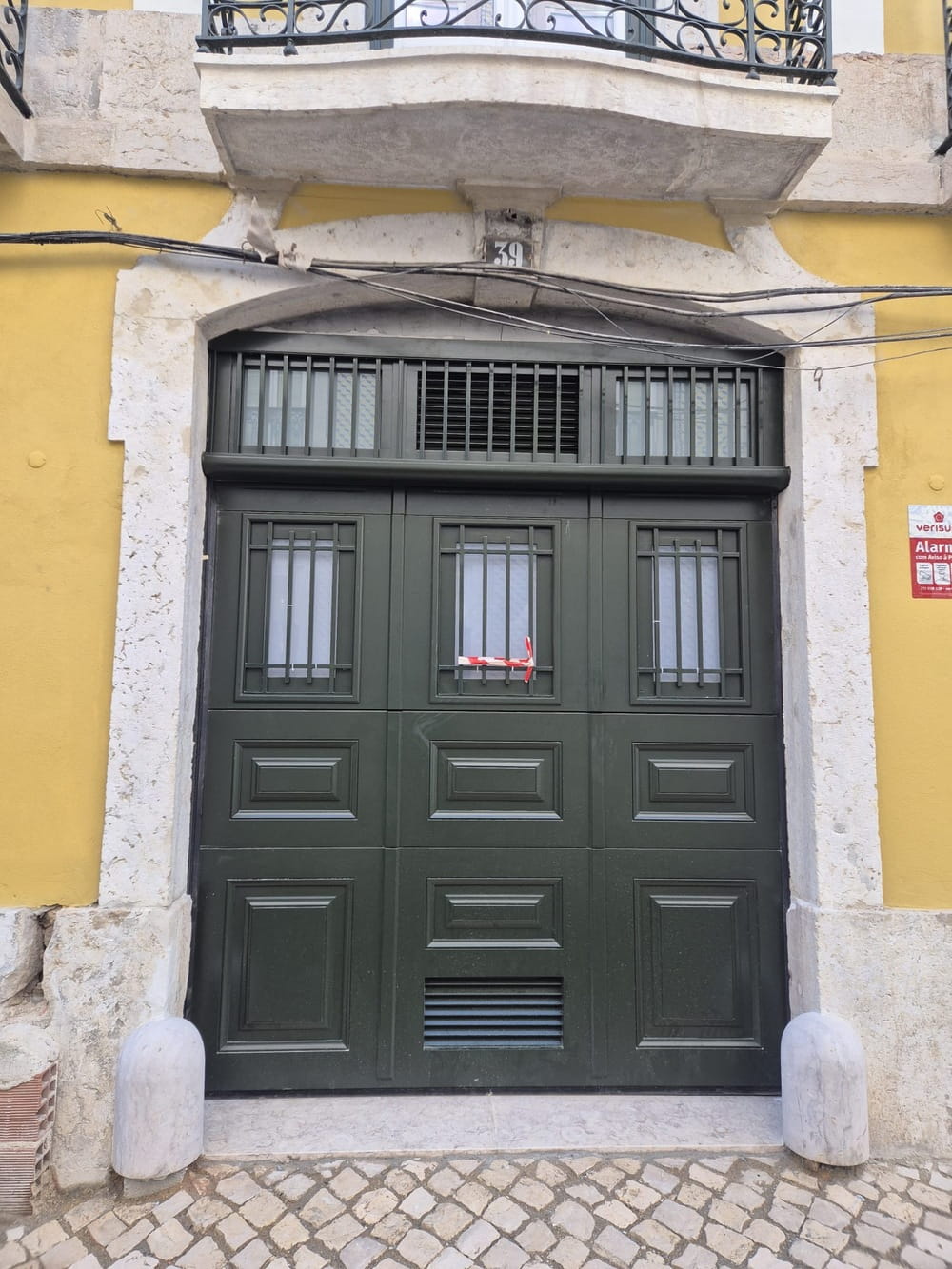 Porta seccionada em madeira de kambala numa fachada em reabilitação em Lisboa
