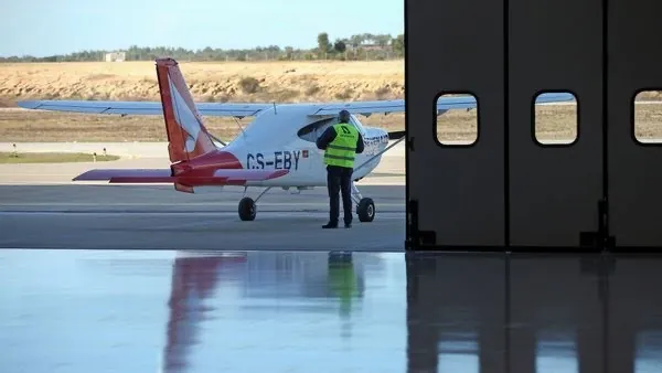Avião visto através do portão de harmónio com visores, no hangar do Aeródromo Municipal de Ponte de Sôr