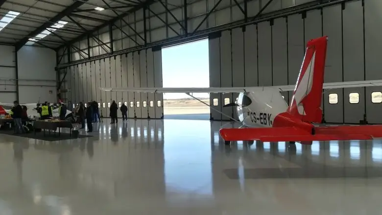 Interior do hangar com a porta de harmónio Apollo parcialmente aberta e os visores ao longo das folhas