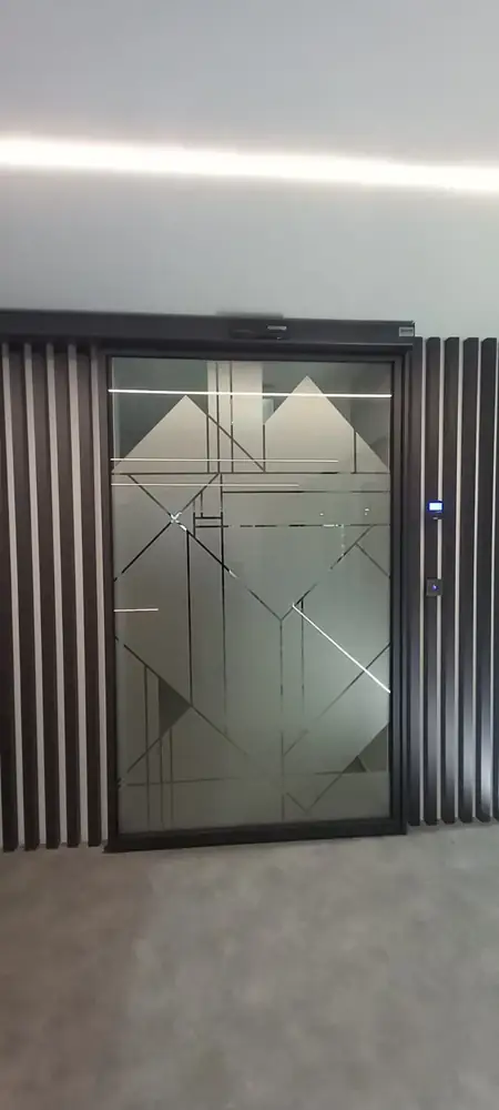 Porta automática deslizante FAAC de uma folha, em tom escuro, integrada numa parede de ripas na sede da Hydro, em Prior Velho