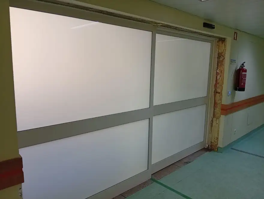 Porta automática de vidro fosco com almofada central num corredor da ULS Entre Douro e Vouga