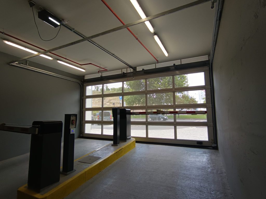 Porta seccionada microperfurada vista do interior da garagem, com barreiras de controlo de acessos
