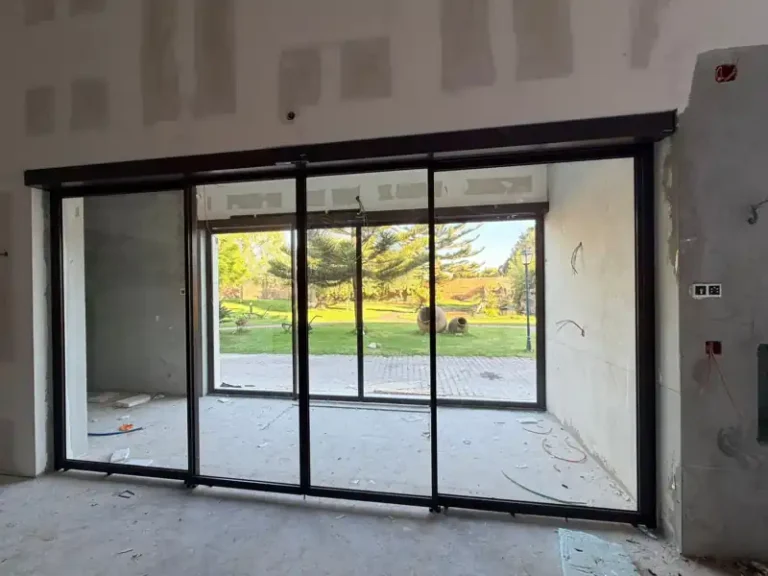 Porta automática deslizante redundante com caixilho RF34 fechada, vista do interior em obra, numa quinta de eventos em Santo André